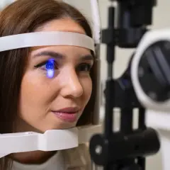 Kobieta podczas badania wzroku soczewki. Niebieskie światło oświetla jej oko, gdy jest badana przez okulistę.