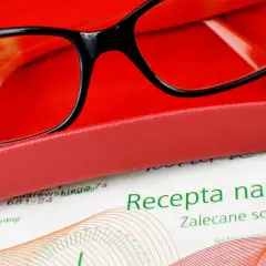 Okulary w etui, obok dokument z nagłówkiem "Recepta na okulary".