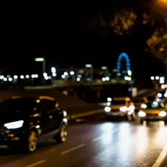 Rozmazane światła samochodów i miejskiego krajobrazu nocą, jakby widziane przez osobę z astygmatyzmem.