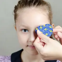 Dziecko z plastrem na oku z motywem samolotów.