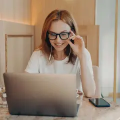 Kobieta w okularach pracuje przy laptopie. Czy jakaś wada wzroku dyskwalifikuje do pracy przy komputerze? Zależy od jej stopnia.