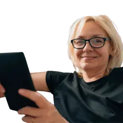 Uśmiechnięta kobieta w okularach trzyma tablet. Czy to objawy prezbiopii? Co to jest i jak sobie z nią radzić?