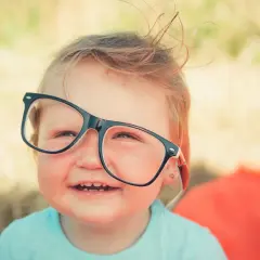 Uśmiechnięte dziecko w okularach. Czy wada wzroku jest dziedziczna? To pytanie nurtuje wielu rodziców.