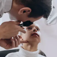 Lekarz bada wzrok dziewczynki, sprawdzając, czy zez może zostać.