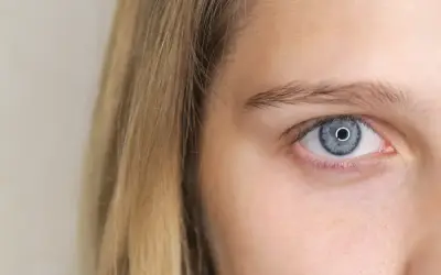 Zbliżenie na niebieskie oko z refleksami, obok blond włosy. Jedno oko mniejsze, ale równie hipnotyzujące.