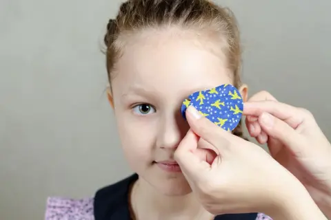 Dziecko z plastrem na oku z motywem samolotów.