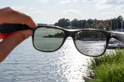 Widok jeziora przez okulary z polaryzacją. Słońce odbija się od wody, tworząc błyszczące refleksy.