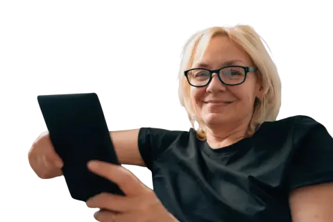 Uśmiechnięta kobieta w okularach trzyma tablet. Czy to objawy prezbiopii? Co to jest i jak sobie z nią radzić?