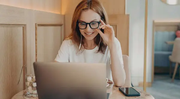 Kobieta w okularach pracuje przy laptopie. Czy jakaś wada wzroku dyskwalifikuje do pracy przy komputerze? Zależy od jej stopnia.