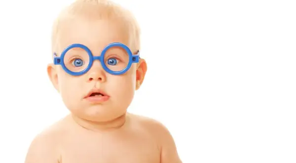 Niebieskie okulary na twarzy niemowlaka, jego oczy zdają się uciekać przy zmęczeniu, jakby szukał chwili wytchnienia.
