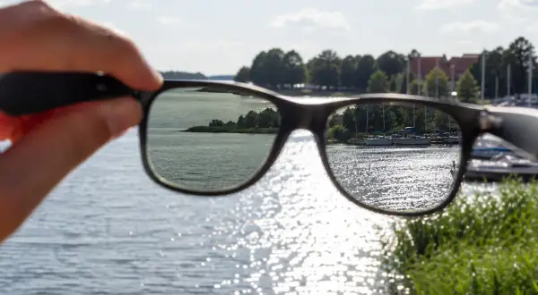 Widok jeziora przez okulary z polaryzacją. Słońce odbija się od wody, tworząc błyszczące refleksy.