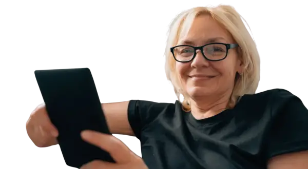Uśmiechnięta kobieta w okularach trzyma tablet. Czy to objawy prezbiopii? Co to jest i jak sobie z nią radzić?