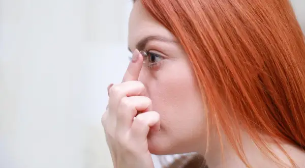 Ruda kobieta zakłada soczewkę na oko. Dawna soczewka na oko, która poprawia wzrok.