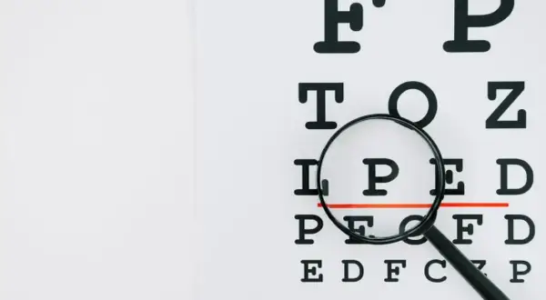 Tablica optometryczna z lupą, badanie wzroku ujawnia astygmatyzm nieregularny.