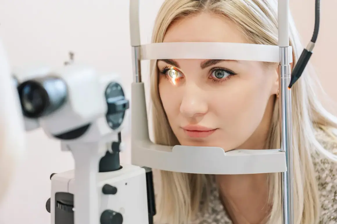 Kobieta z blond włosami poddawana badaniu wzroku. Okular na jedno oko jest częścią urządzenia diagnostycznego.