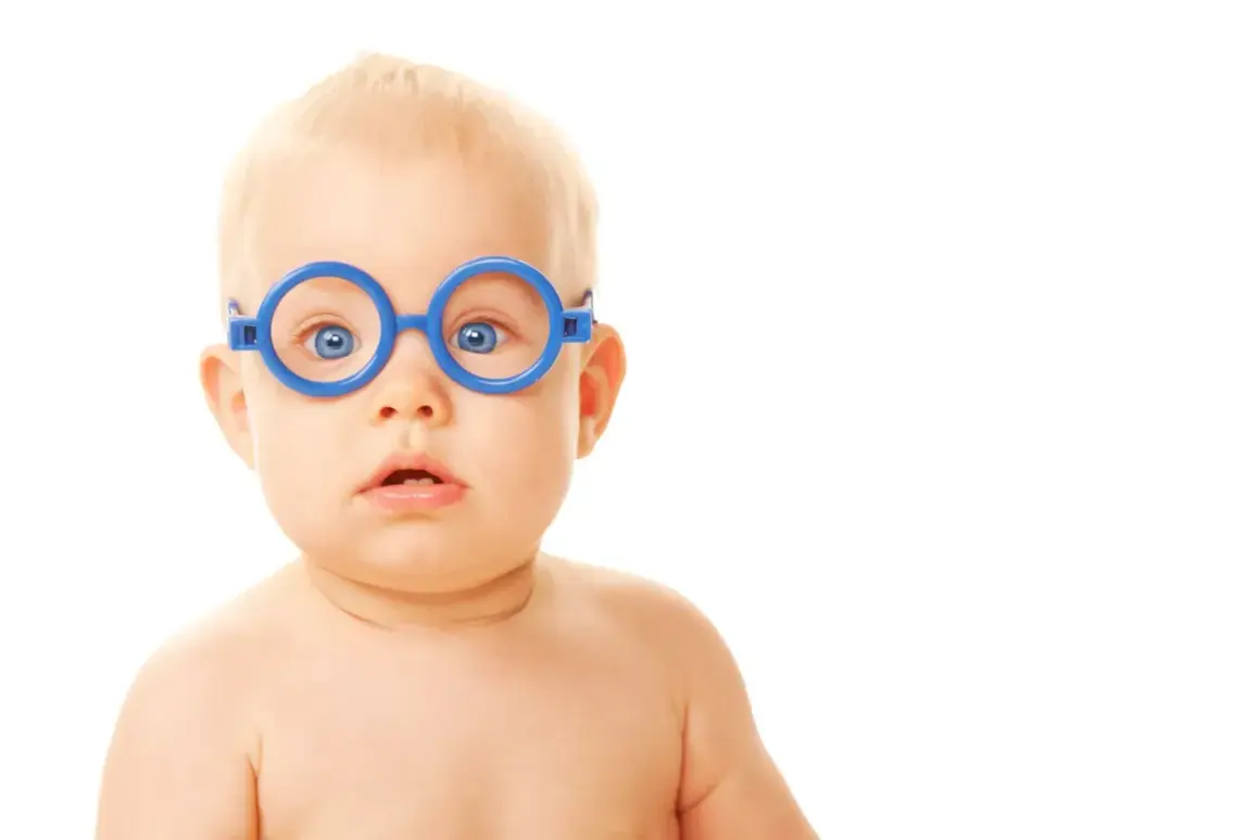 Niebieskie okulary na twarzy niemowlaka, jego oczy zdają się uciekać przy zmęczeniu, jakby szukał chwili wytchnienia.