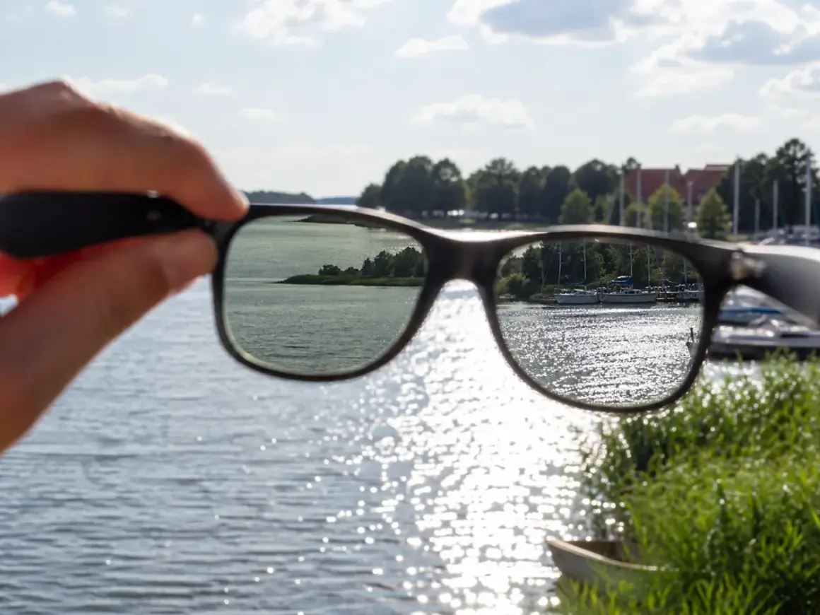 Widok jeziora przez okulary z polaryzacją. Słońce odbija się od wody, tworząc błyszczące refleksy.