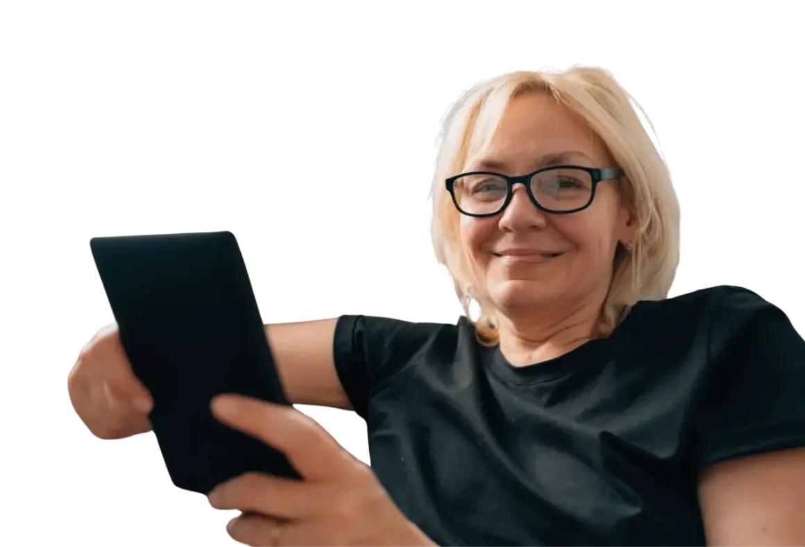 Uśmiechnięta kobieta w okularach trzyma tablet. Czy to objawy prezbiopii? Co to jest i jak sobie z nią radzić?