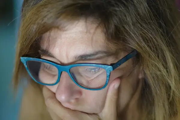 Kobieta w okularach, które wydają się za mocne do dali, zamyślona.